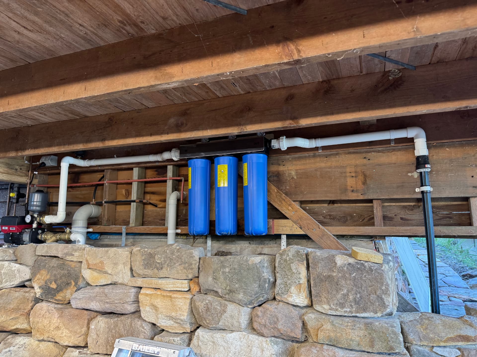 Triple cartridge whole-of-house rainwater filtration bank and pressure pump installed under a bushland home