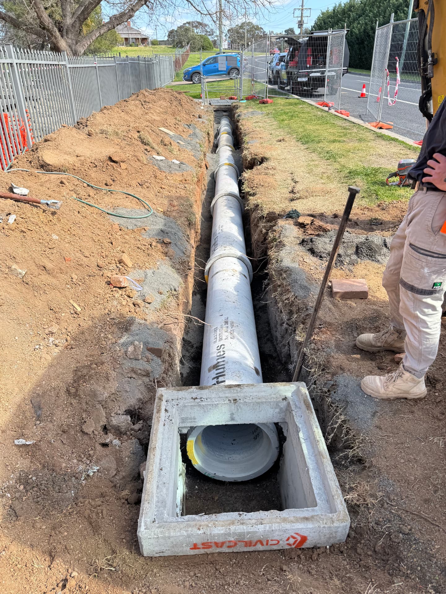 Precast concrete junction pit set over a reinforced concrete stormwater pipe in an open verge trench
