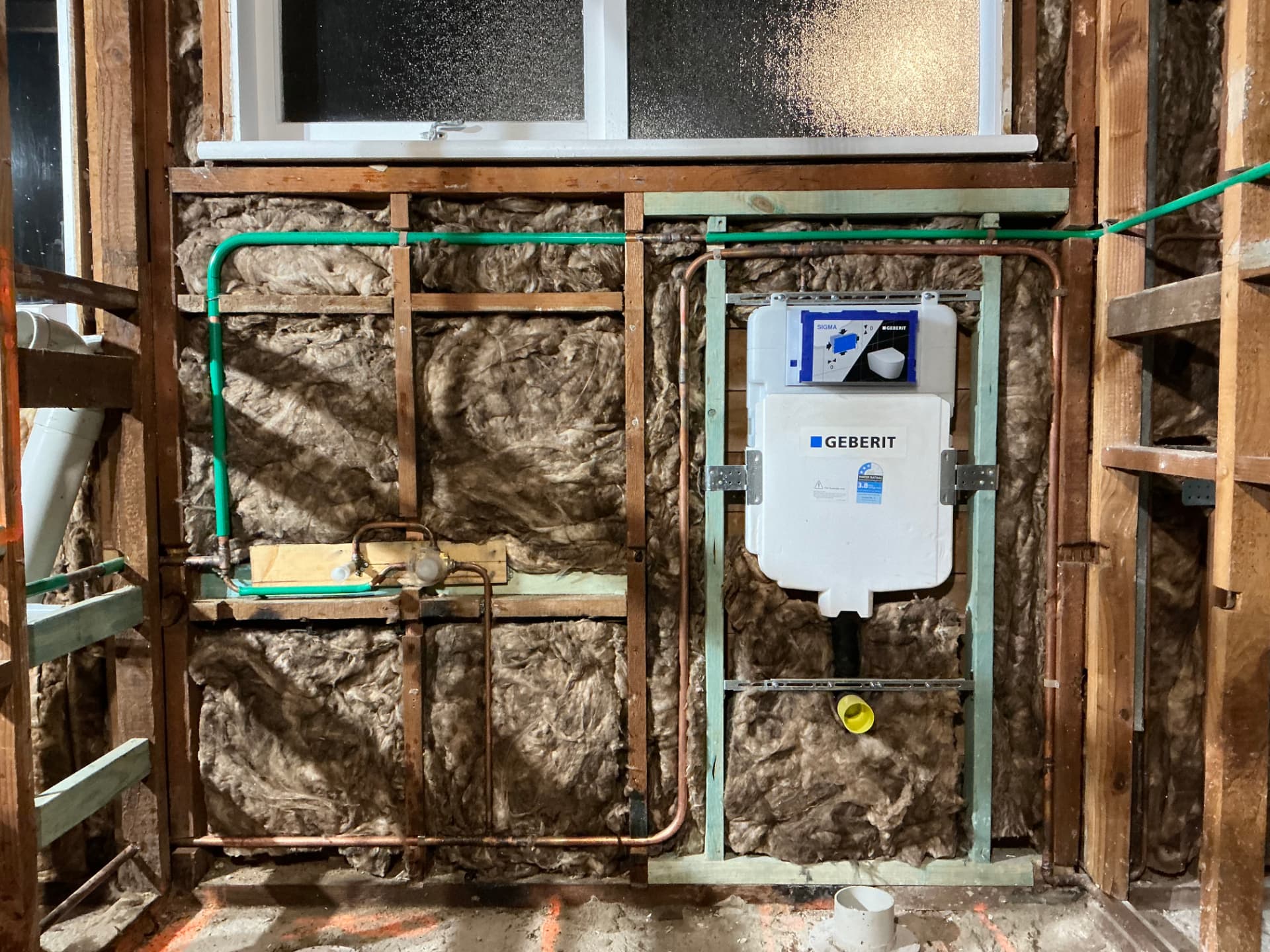 Bathroom wall framing with copper and PEX water service rough-in and an in-wall Geberit cistern frame installed